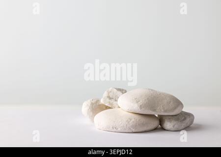 Kleiner Stapel weißer Kieselsteine auf heller Oberfläche mit weichem Kopierraum für Spa-Wellness und minimalistischem Texturhintergrund Stockfoto