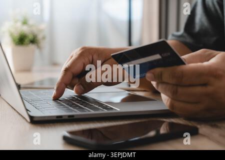 Person, die eine Kreditkarte besitzt und während eines Online-Kaufs Zahlungsdaten auf einem Laptop eingibt, die den Kaufvorgang im E-Commerce, die digitale Transaktion veranschaulicht, Stockfoto