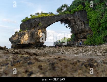 Flacher Blick auf die massive Kalkstein Natural Bridge (Howrah Bridge) am Lakshmanpur Beach mit einem verschwommenen Korallenfelsen im Vordergrund, Neil Island, Indien. Stockfoto