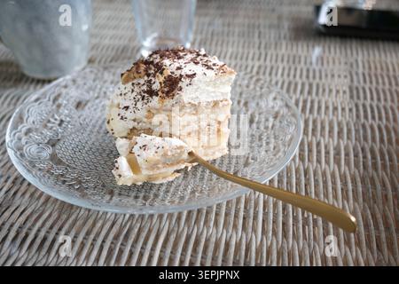Eine Portion Kuchen auf einem Teller mit mehreren Schichten Sahne. Stockfoto