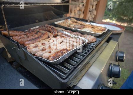 Fleisch, Würstchen, Gemüse auf einem Gasgrill grillen. Stockfoto