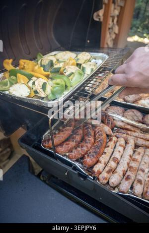 Fleisch, Würstchen, Gemüse auf einem Gasgrill grillen. Stockfoto