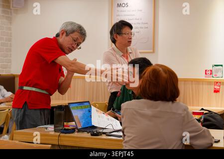Taipei, Taiwan - 24. September 2025: Ein Mann demonstriert ein Muskeltestgerät, eine Grauzone-Direktverkaufsszene, die in taiwanischen Fast-Food-Ketten üblich ist. Stockfoto