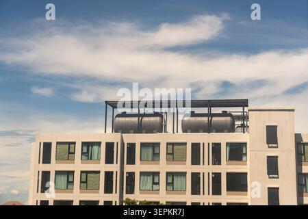Ein modernes Apartmentgebäude mit einer eleganten Fassade mit mehreren Fenstern und Balkonen, ausgestattet mit Solar-Warmwasserbereitern auf der Dachterrasse, eingestellt gegen ins Stockfoto