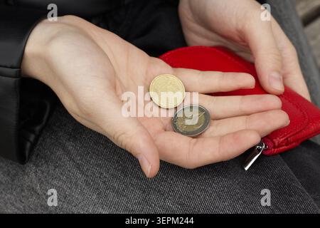 Eine Frau, die Euro-Münzen in Palme hält, neben der roten Brieftasche Stockfoto