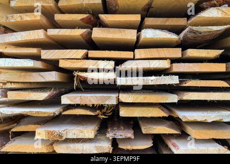 Die Holzstruktur und der Hintergrund der Holzbretter werden durch Schnittholzdielen gebildet, die in einer Nähe gestapelt werden. Rohstoffe aus dem Sägewerk sind bereit für Nachteile Stockfoto
