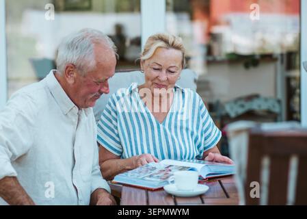 Lächelndes älteres Paar, das im Garten Kaffee genießt. Stockfoto