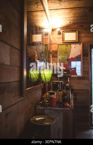 Eine warme und einladende Szene mit einem Innenraum aus Holz, beleuchtet durch eine dekorative grüne Lampe und Ambient-Deckenleuchten, die eine gemütliche Atmosphäre schaffen Stockfoto