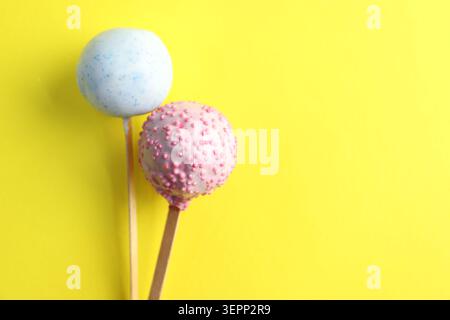 Zwei leckere Cake Pops mit Streuseln auf gelbem Hintergrund, Draufsicht. Leerzeichen für Text Stockfoto