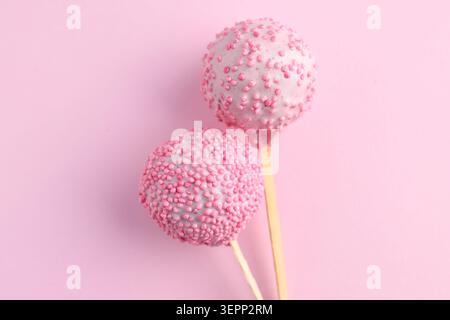 Zwei leckere Kuchen-Pops mit Streuseln auf rosa Hintergrund, Draufsicht Stockfoto