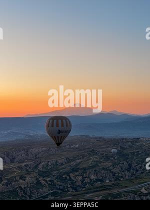 Dieses atemberaubende Bild zeigt Heißluftballons, die während eines wunderschönen Sonnenaufgangs über der einzigartigen Landschaft Kappadokiens schweben. Stockfoto