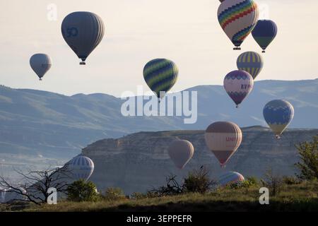 Farbenfrohe Heißluftballons schweben ruhig über die einzigartigen Felsformationen und üppigen Täler von Kappadokien, Türkei. Stockfoto