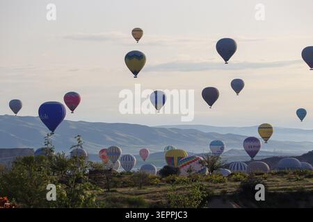 Ein atemberaubender Blick auf verschiedene Heißluftballons, die über die einzigartige Landschaft Kappadokiens in der Türkei treiben. Stockfoto