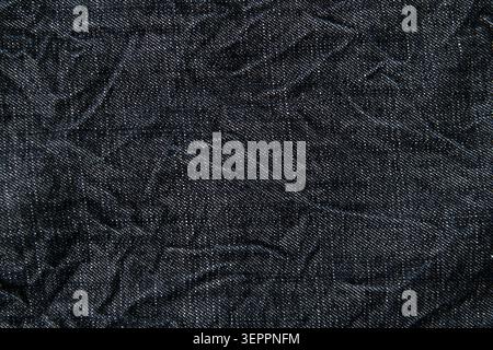 Faltenmuster aus schwarzem Denim in Nahaufnahme für Kleidung, Mode und Hintergrund Stockfoto