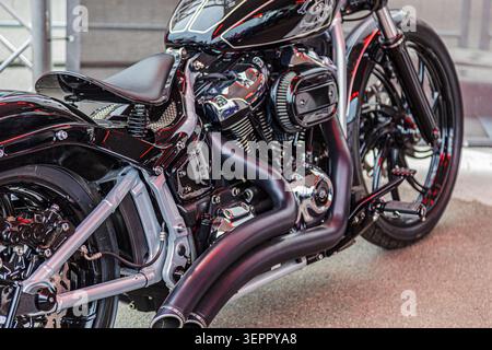 Maßgeschneidertes Cruiser-Motorrad mit Hochglanzlackierung und Chromakzenten, die das Design eines V-Twin-Motors, einen niedrigen Lenker, breite Reifen und ein elegantes Urban-Design zeigen Stockfoto