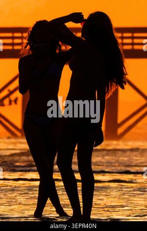 Isle Of Palms, Usa. Juni 2026. Zwei junge Frauen posieren für Selfies im Sonnenaufgang über dem Atlantischen Ozean am Front Beach, 15. Juni 2026 in Isle of Palms, South Carolina.Credit: Richard Ellis/Richard Ellis/Alamy Live News Stockfoto