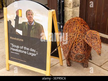 Ein hölzernes A-Rahmen-Schild, das das Lager von Hawkstone mit einem Foto von Jeremy Clarkson neben einer dekorativen, gewebten Korbskulptur eines Schweins markiert Stockfoto