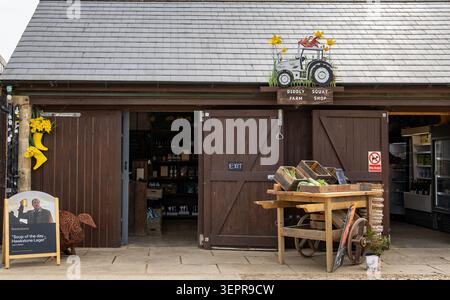 Der Eingang zum Diddly Squat Farm Shop in den Cotswolds mit Holztüren, einem Schaufelwagen und Kisten für Produkte Stockfoto