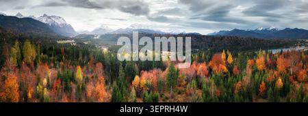 Farbenfroher, malerischer Herbstwald mit wunderschönem bewölktem Himmel und Bergen im Hintergrund, Panoramablick auf die Landschaft aus der Luft Stockfoto