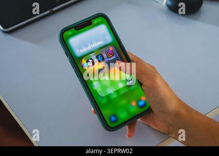 Balikpapan, Indonesien - Mai 31 2026. Eine Nahaufnahme einer Hand, die ein Smartphone in einem grünen Gehäuse hält und einen Ordner mit dem Namen „soziale Medien“ anzeigt. Stockfoto