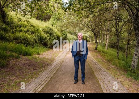 Seniorenmann, der allein über das Leben in einem ruhigen Naturpark nachdenkt Stockfoto