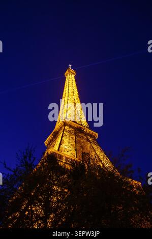 Paris, Frankreich - 4. April 2026: Eiffelturm leuchtet in goldenem Licht vor tiefblauem Nachthimmel. Stockfoto