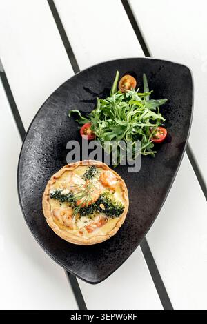 Lachs und Brokkoli Quiche mit Salat gesunde Mahlzeit auf weißem Kaffeetisch auf ibiza Stockfoto