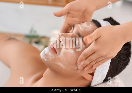 Frau, die Schaum auf das Gesicht des Mannes aufträgt, in der Badewanne zu Hause, Nahaufnahme Stockfoto