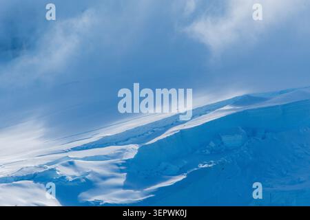 Eine beschauliche antarktische Landschaft in der Nähe des Hafens Mikkelsen auf Trinity Island, mit starken Reflexen, zerklüfteten Bergen und beeindruckenden Eisbergen Stockfoto