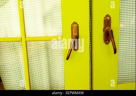 Nahaufnahme von kunstvollen antiken Türgriffen auf einer verwitterten Holztürfläche Stockfoto