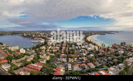 Luftaufnahme von Manly Beach und Manly Cove mit Wohngebäuden, Sandstränden und Booten im Hafen unter bewölktem Himmel in Sydney, New South Wa Stockfoto