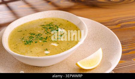 Köstliche hausgemachte Hühnerbrühe sieht in einer Keramikschale sehr frisch aus. Authentische warme klare Suppe sorgt für einen appetitlichen Stil für ein gesundes Mittagessen. Stockfoto