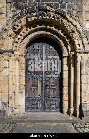 Historische normannische Westtür mit kunstvoll geschnitzten Chevron-Motiven und Mühlenkreuzen in der All Saints Church in Bakewell, Derbyshire Stockfoto