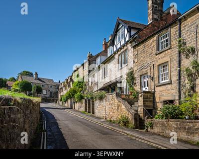 Gesäumt von historischen Sandstein- und Kalksteinterrassenhäusern auf dem steilen Hügel der North Church Street in Bakewell, Peak District Stockfoto