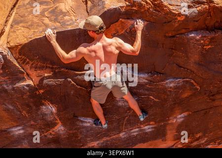 Ein junger Kletterer begibt sich beim Bouldern auf der Black Box. Big Bend Bouldergebiet, Moab, Utah. Stockfoto