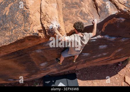 Ein junger Kletterer begibt sich beim Bouldern auf der Black Box. Big Bend Bouldergebiet, Moab, Utah. Stockfoto
