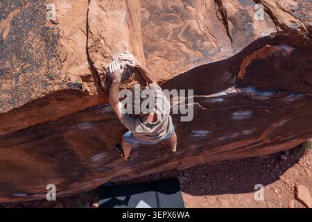Ein junger Kletterer begibt sich beim Bouldern auf der Black Box. Big Bend Bouldergebiet, Moab, Utah. Stockfoto
