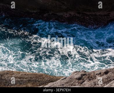 Küstenfelsen von Shitiping. Blaue Ozeanwellen krachen in Taiwan gegen dunkle felsige Klippen. Meeresschaum wirbelt im Wasser. Stockfoto
