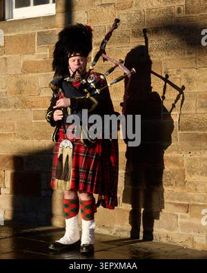 Edinburgh, Schottland, Vereinigtes Königreich - 19. Januar 2026: Dudelsack in traditioneller Highland-Kleidung spielt Dudelsack an einer Steinmauer Stockfoto
