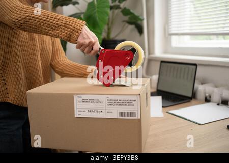 Unternehmerin versiegelt Kartonschachtel mit Verpackungsband, die Boxen für die Lieferung vorbereiten. Nahaufnahme Stockfoto