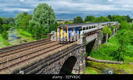 Ein Dieselzug der britischen Eisenbahnklasse 156 überquert das Viadukt über den Sankey-Kanal im Linearpark Sankey Valley bei Warrington Stockfoto