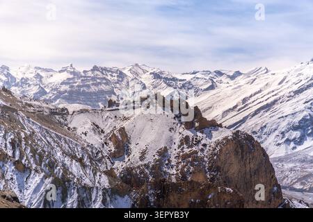 Weite Panorama-Winterlandschaft des alten Dhankar-Klosters auf einer zerklüfteten Klippe, umgeben von schneebedeckten Himalaya-Bergen im Spiti-Tal, Indien. Stockfoto