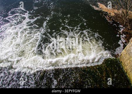 Hochwasser von einem Sturm durchtränkte Fußweg schäumend und floss schnell in einen nahegelegenen Fluss Stockfoto