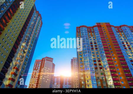 Flacher Blick auf moderne, farbenfrohe Wohnhäuser in einem neuen Viertel bei Sonnenuntergang der goldenen Stunde mit Sonnenschein und blauem Himmel Stockfoto
