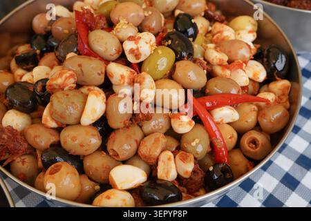 saftige gemischte Oliven in einer Schüssel mit Knoblauch- und Chili-Marinade. Lebensmittelmarkt-Produkte Stockfoto