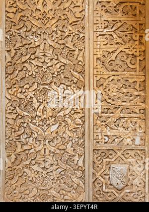 Eine detaillierte Ansicht von geschnitzten arabesken Blumenmustern und arabischer Kalligraphie-Schrift auf einer Gipswand in der Alhambra in Granada, Spanien Stockfoto