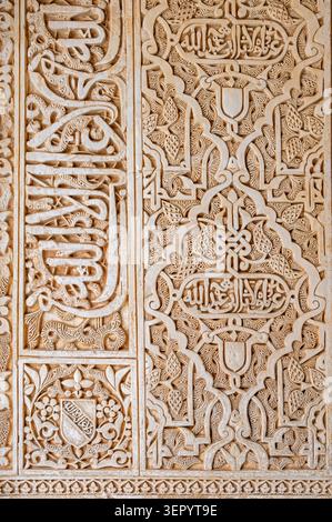 Eine detaillierte Ansicht von geschnitzten arabesken Blumenmustern und arabischer Kalligraphie-Schrift auf einer Gipswand in der Alhambra in Granada, Spanien Stockfoto