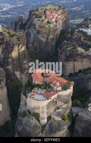 Blick aus der Vogelperspektive auf die historischen Meteora-Klöster auf steilen Felssäulen mit roten Ziegeldächern und Steinmauern, umgeben von üppigen grünen Tälern Stockfoto