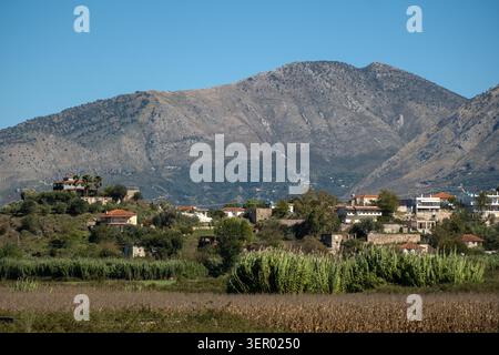 30.09.2024, Albanien, Vlora, Shelegar - Ein Dorf auf einem Hügel vor einer Bergkette, mit Feldern im Vordergrund. 00A240930D1204CAROEX.JPG [MODUS Stockfoto