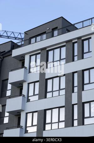 Modernes mehrstöckiges Apartmentgebäude mit eleganten architektonischen Details, Balkonen und großen Fenstern vor klarem Himmel, die urb darstellen Stockfoto